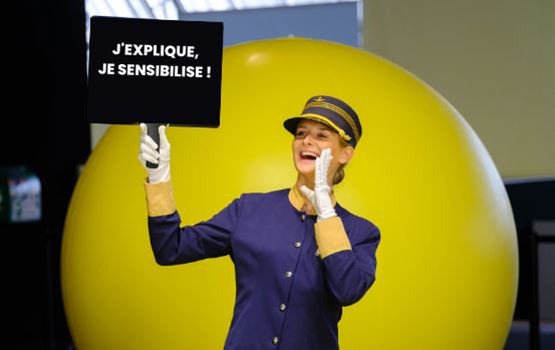 Image of a town crier at a trade fair with an "I explain, I raise awareness" sign